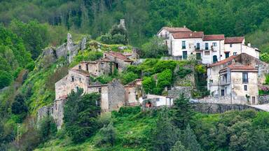 A hillside village with stone buildings and lush greenery.