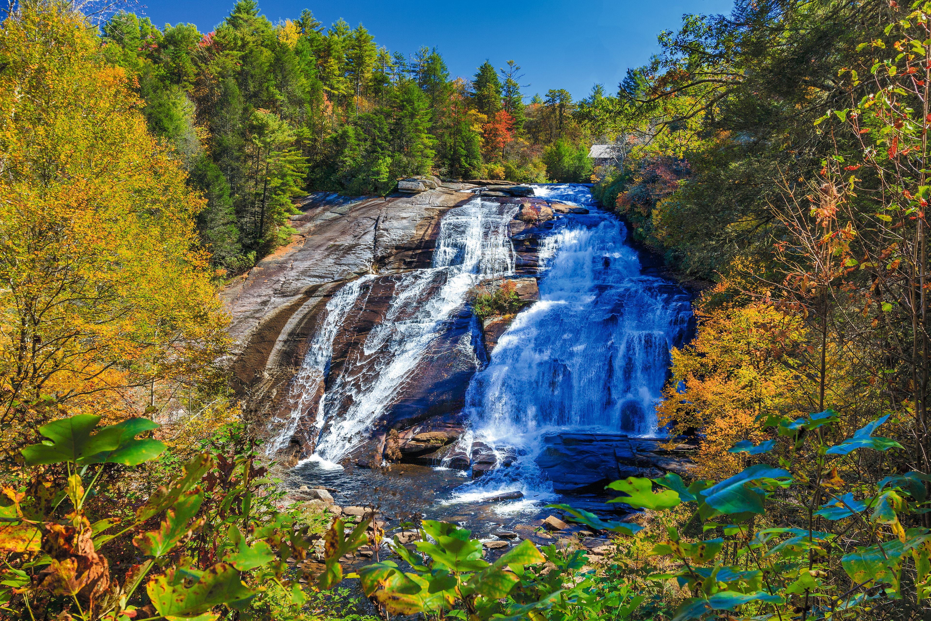A waterfall cascading over a rocky cliff surrounded by autumn-colored trees.