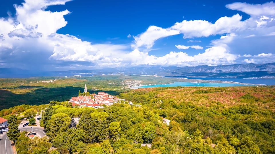 A coastal town with a church, lush greenery, and a clear blue sky.