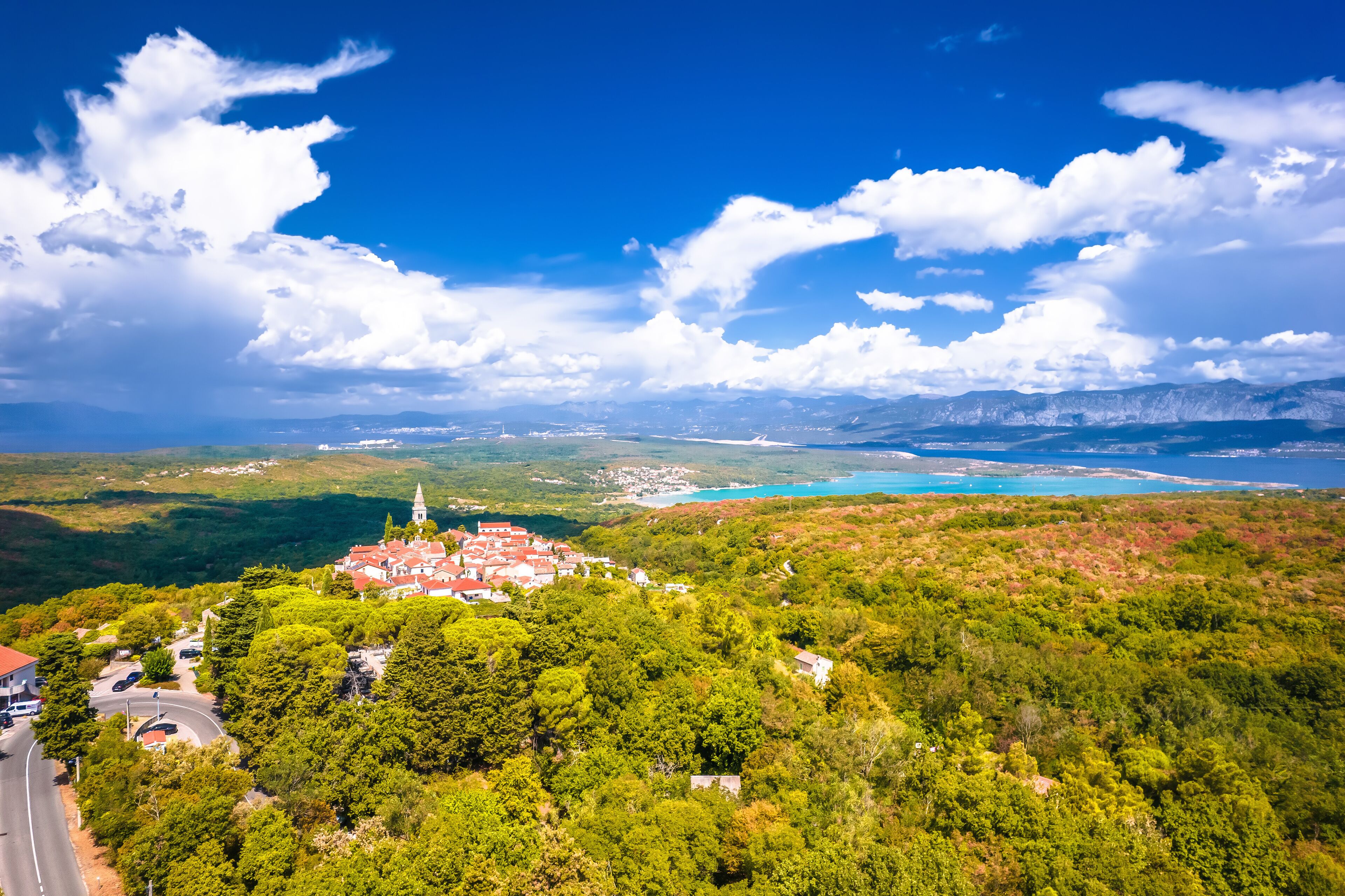 A coastal town with a church, lush greenery, and a clear blue sky.