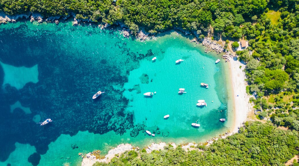 An aerial view of the Blue Lagoon at Plaža Krušćica and Tarej Beach on the island of Cres, showcasing their fantastic turquoise waters and surrounding islands. Boats dot the serene lagoon