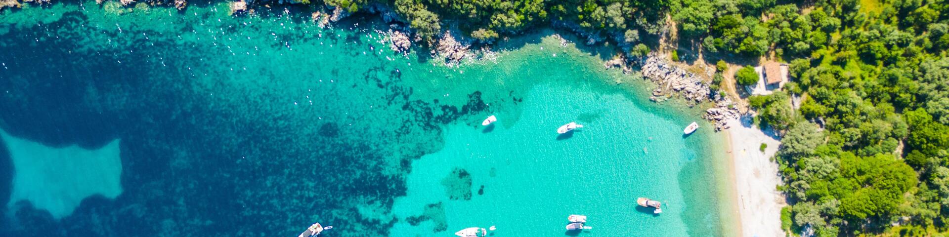 An aerial view of the Blue Lagoon at Plaža Krušćica and Tarej Beach on the island of Cres, showcasing their fantastic turquoise waters and surrounding islands. Boats dot the serene lagoon