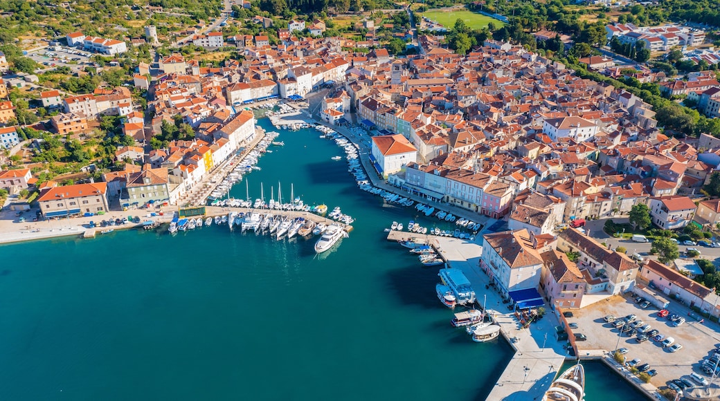 Un pueblo costero con un puerto deportivo, casas escalonadas y un puerto azul cristalino.