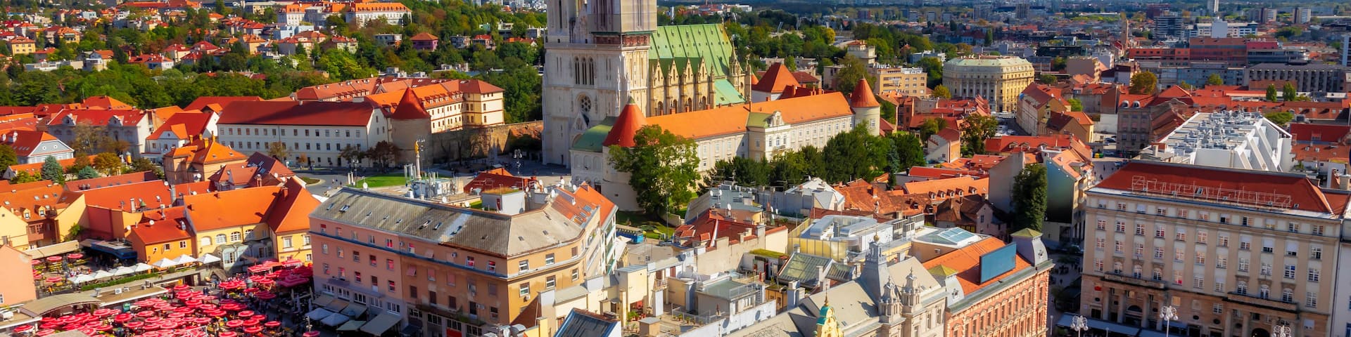 A cityscape with a prominent church tower, a bustling square with market stalls, and a variety of colorful buildings.