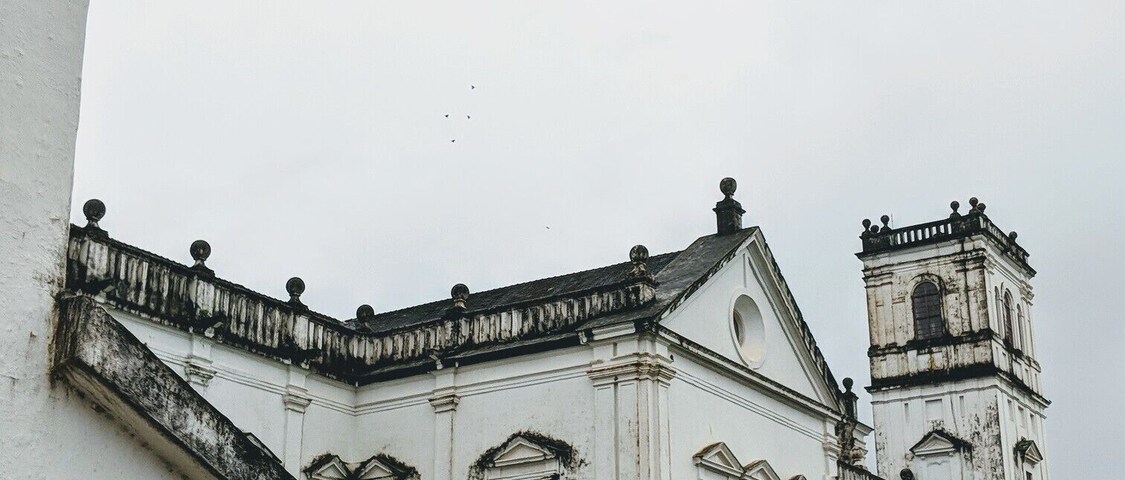 Una iglesia histórica con un campanario y fachada blanca.