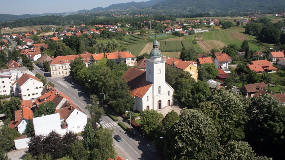 A town with a prominent church, red-roofed buildings, and surrounding green fields.