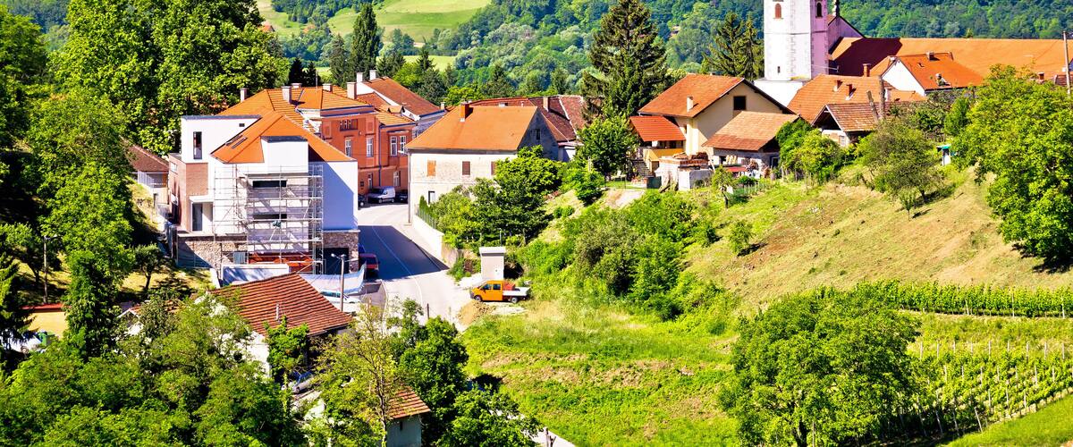 A village with a prominent church, vineyards, and rolling hills.
