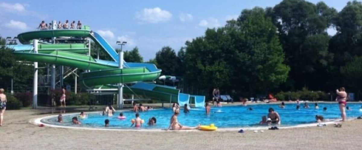 A water park with a green water slide and a swimming pool.