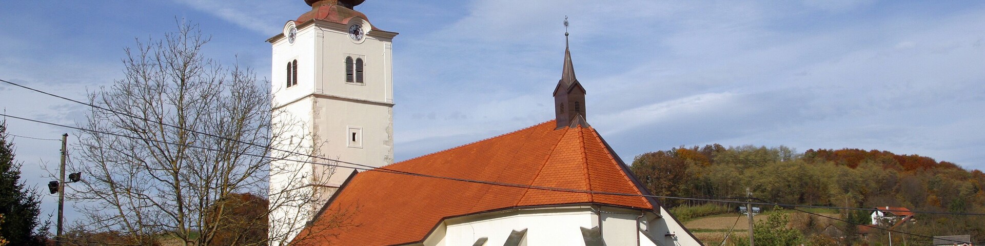 A church with a red-tiled roof and a bell tower with multiple domes.