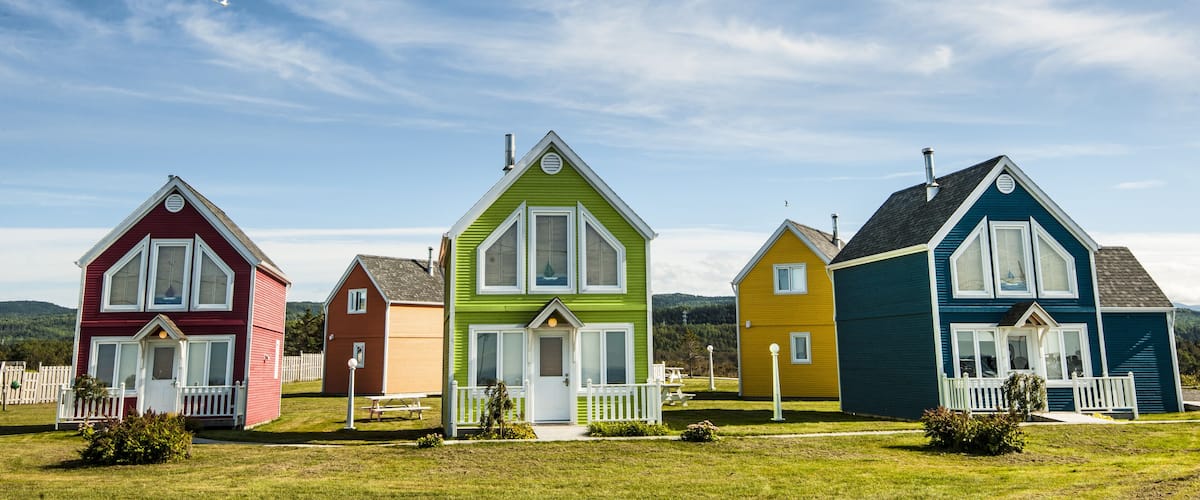 A row of colorful houses with white trim and picket fences.