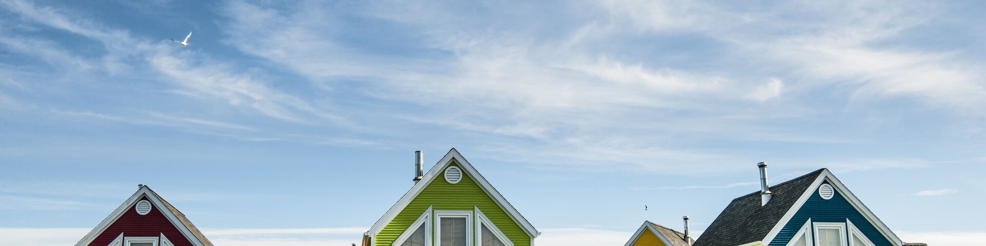 A row of colorful houses with white trim and picket fences.