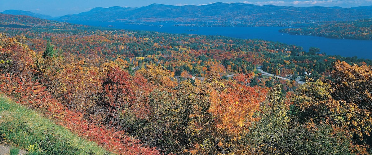 A mountainous landscape with a lake and autumn foliage.