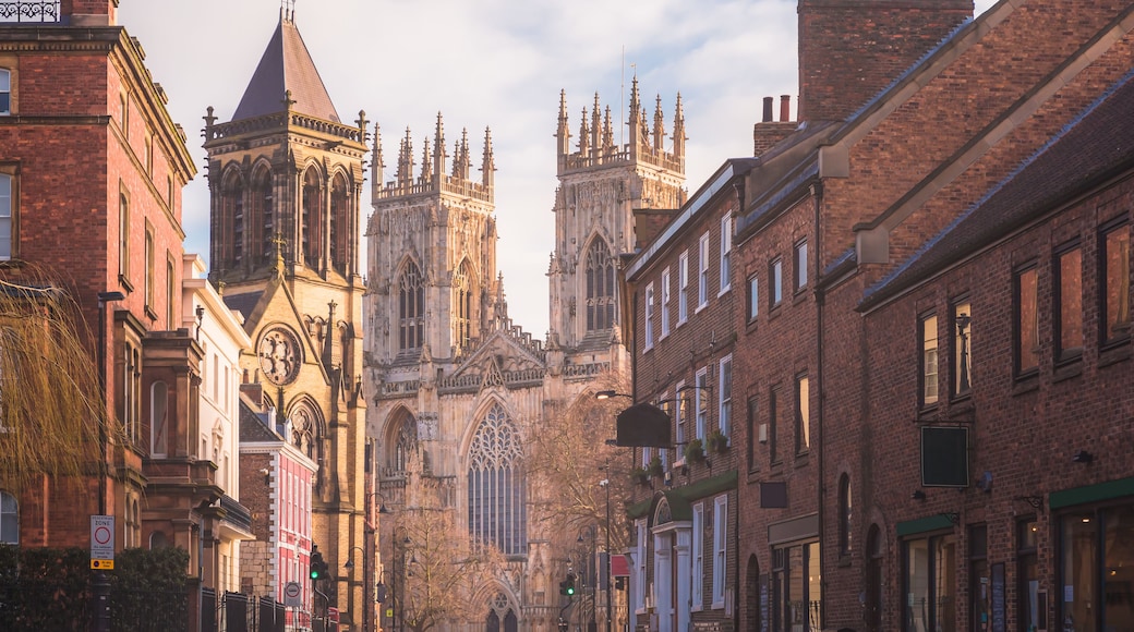A historic street with Gothic architecture, including a prominent church with a tall spire and intricate stonework.