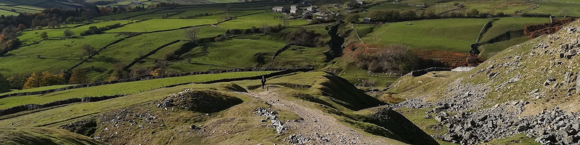 A valley with green fields, stone walls, and scattered buildings.