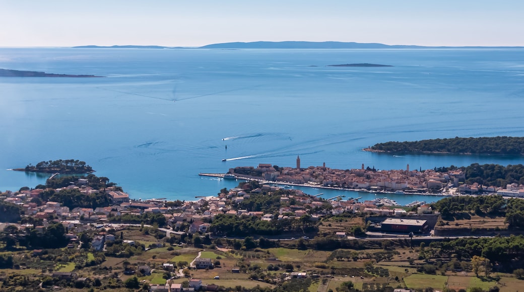 A coastal town with a marina, boats, and a clear view of the surrounding water and distant islands.
