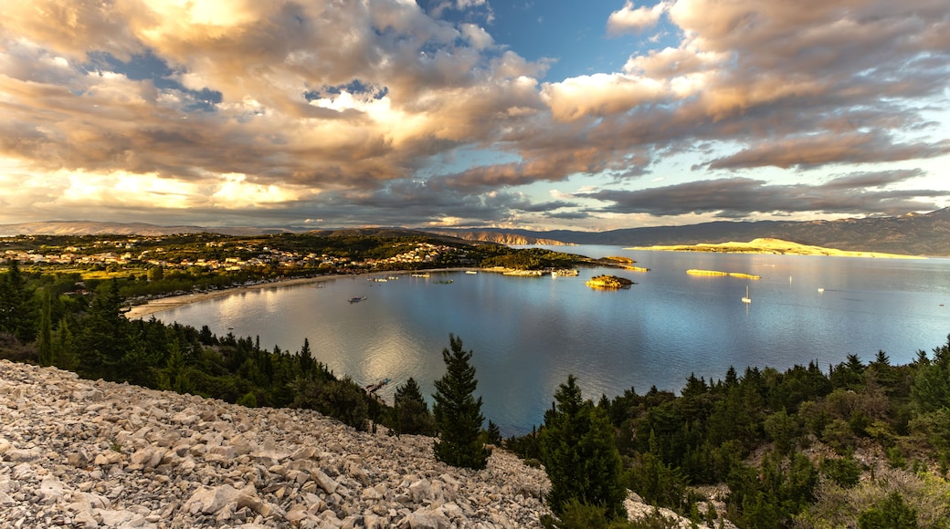 A lake surrounded by mountains, a town with buildings, and a rocky foreground.