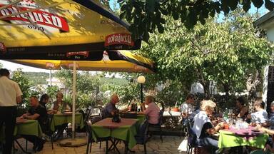 An outdoor dining area with tables and chairs under a large yellow umbrella.
