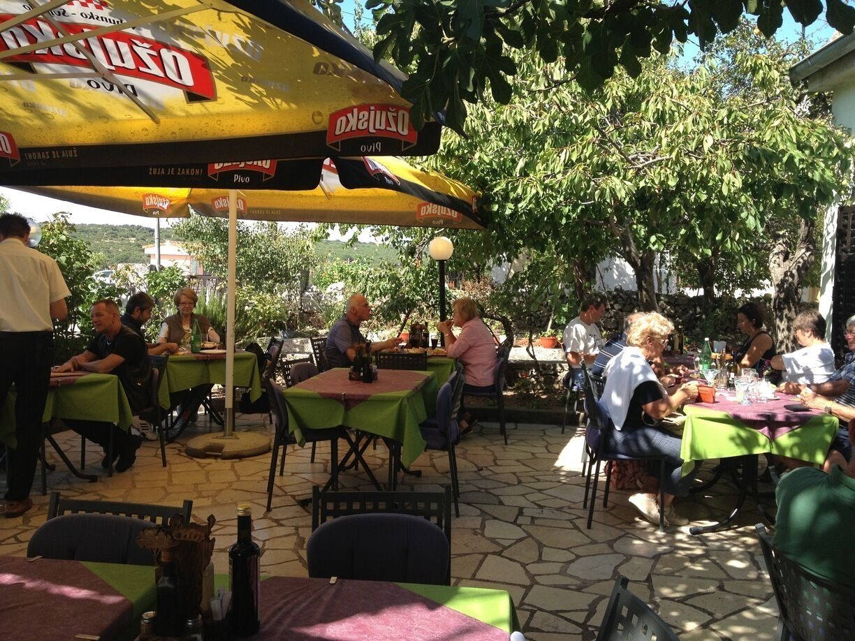 An outdoor dining area with tables and chairs under a large yellow umbrella.