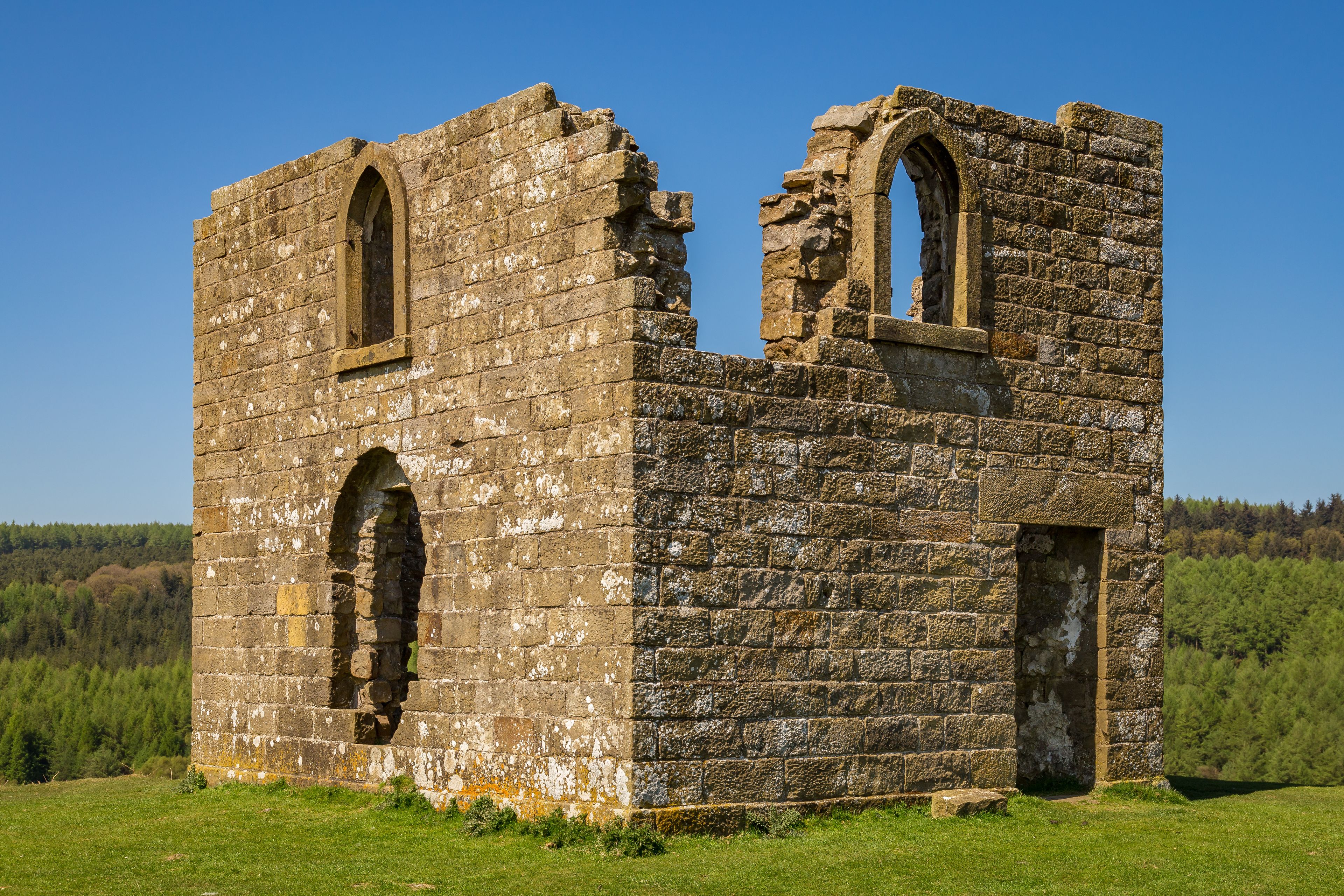 A stone ruin with arched windows and a partially intact wall.