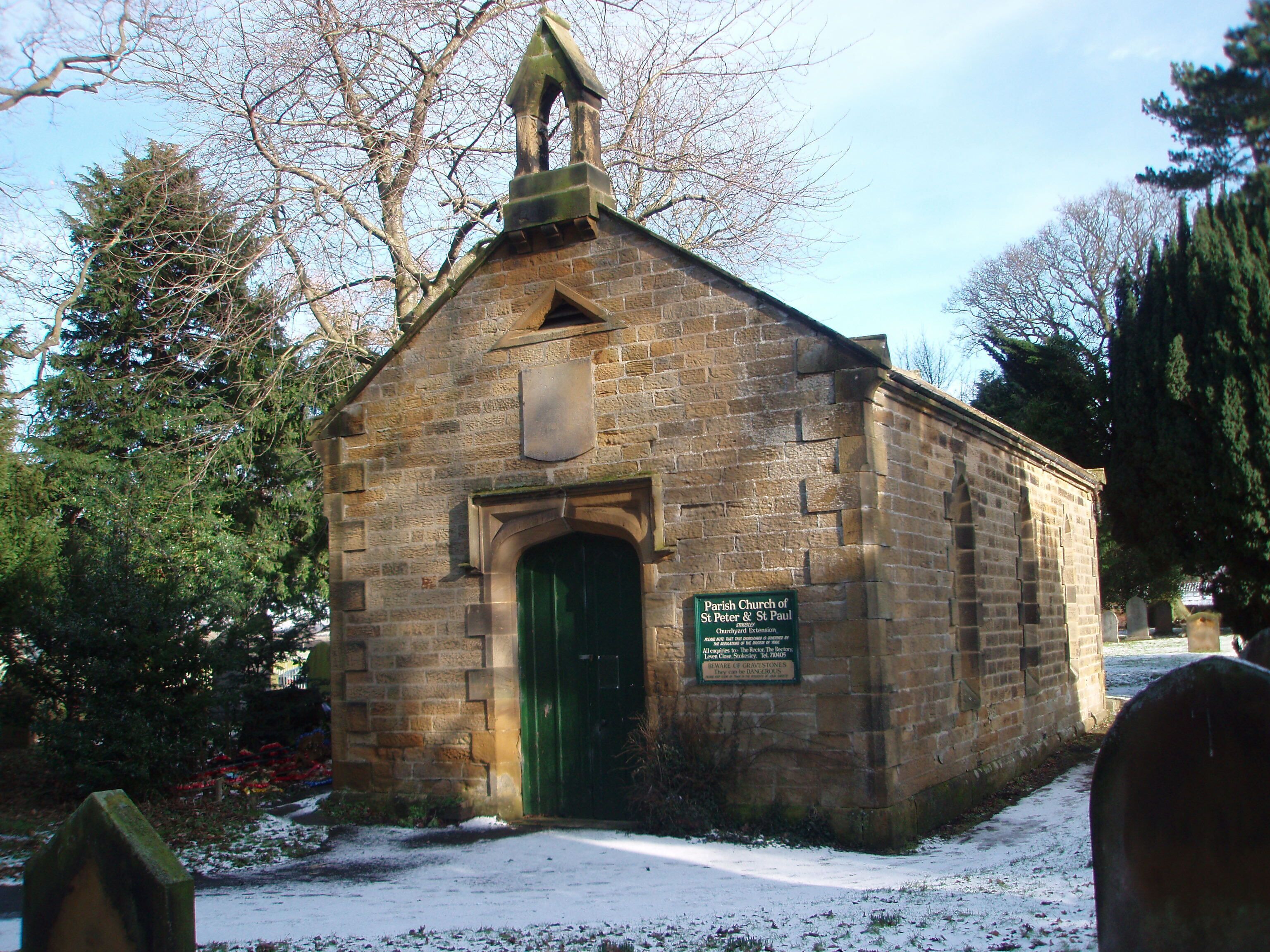 A small stone church with a green door and a sign indicating it is the Parish Church of St Peter & St Paul.