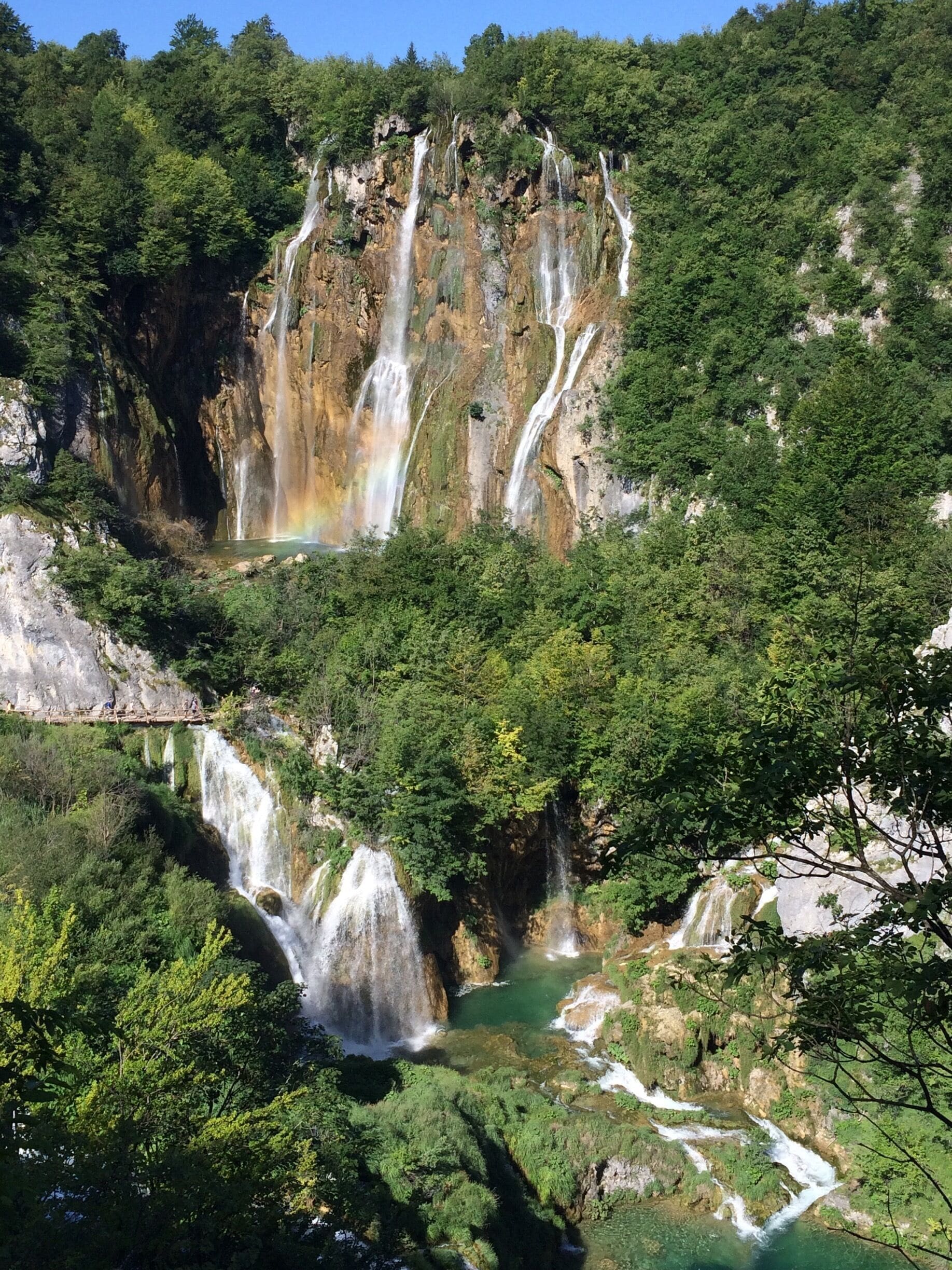 A multi-tiered waterfall surrounded by lush greenery.