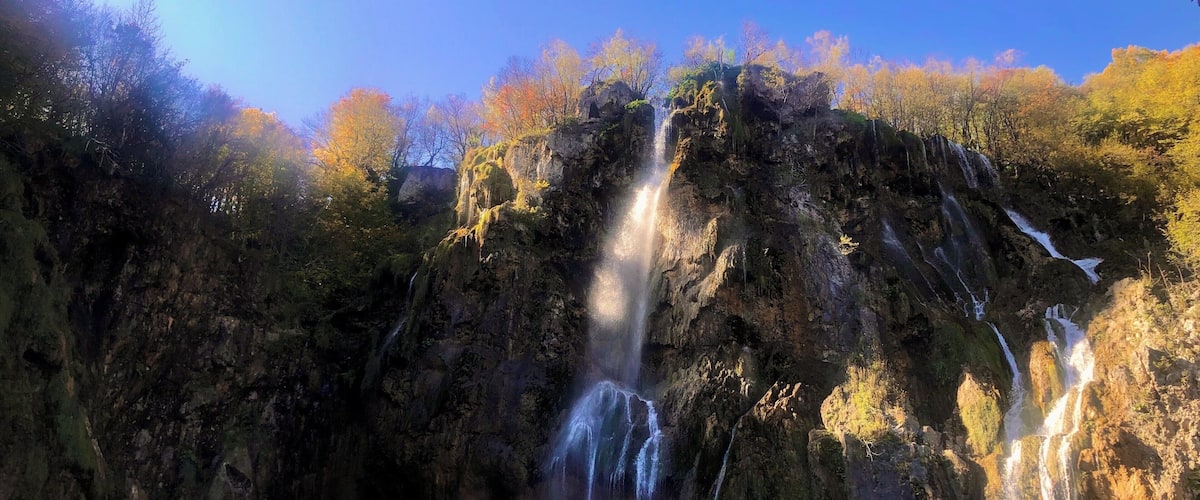 A waterfall cascading down a rocky cliff surrounded by autumn-colored trees.