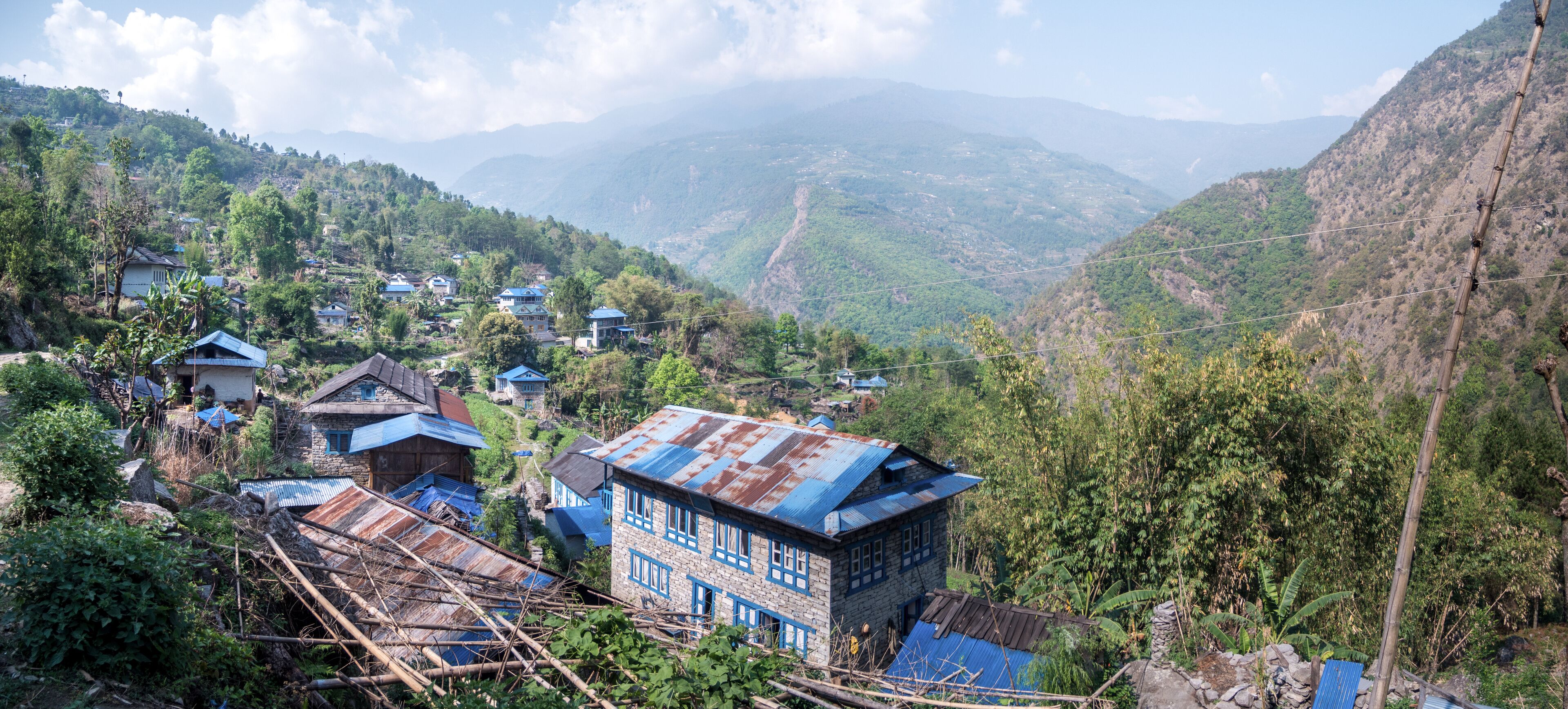 A mountainous village with traditional houses, lush greenery, and distant hills.
