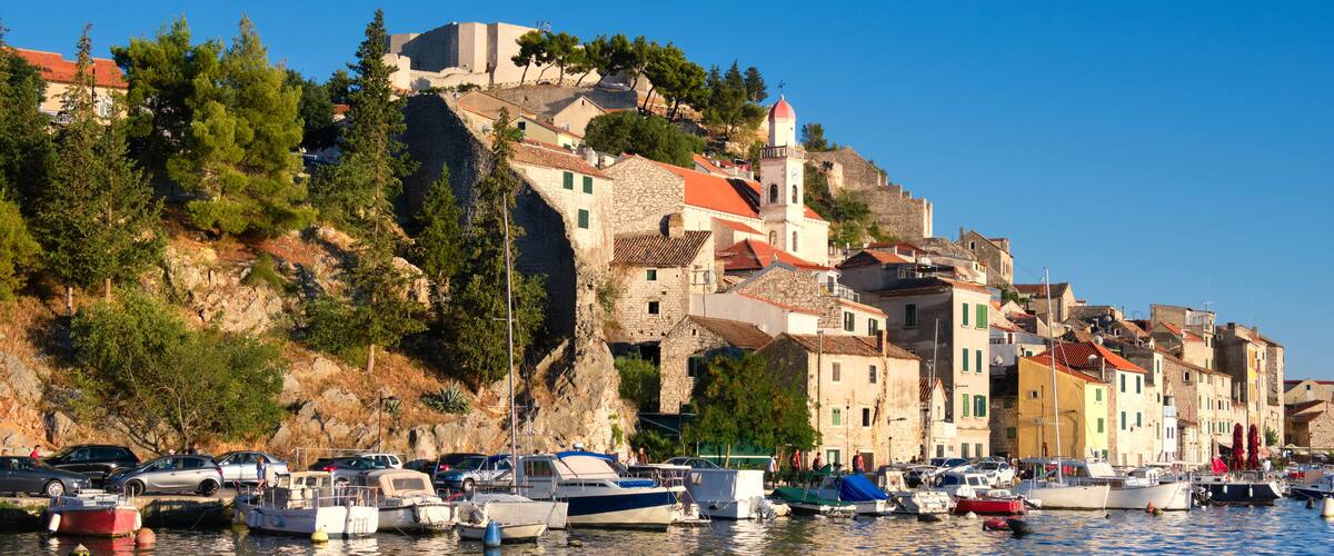 Dramalj, village in Crikvenica, Croatia. Summer holiday destination, view from across the sea. Shore And Boats On Adriatic Coastline with reflection.