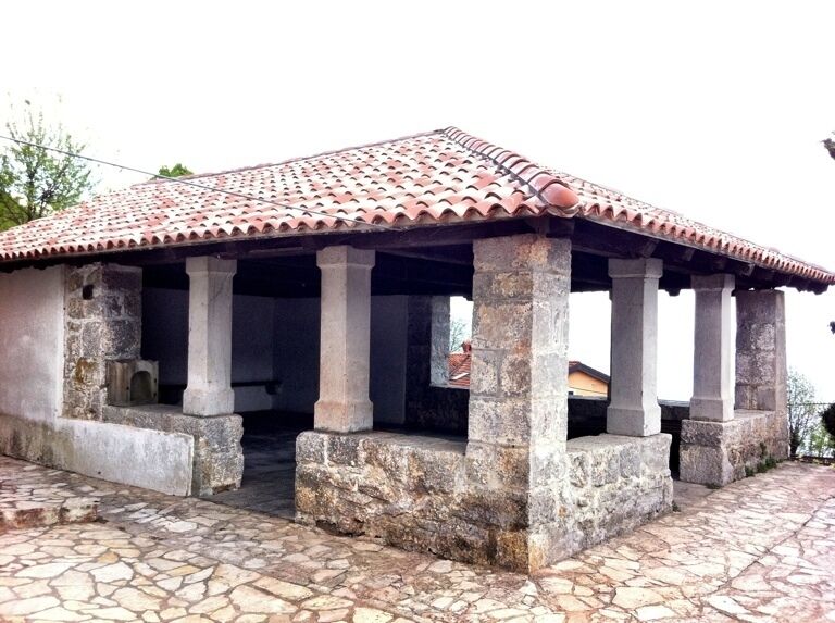 A stone building with a tiled roof and columns.
