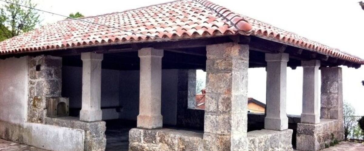 A stone building with a tiled roof and columns.