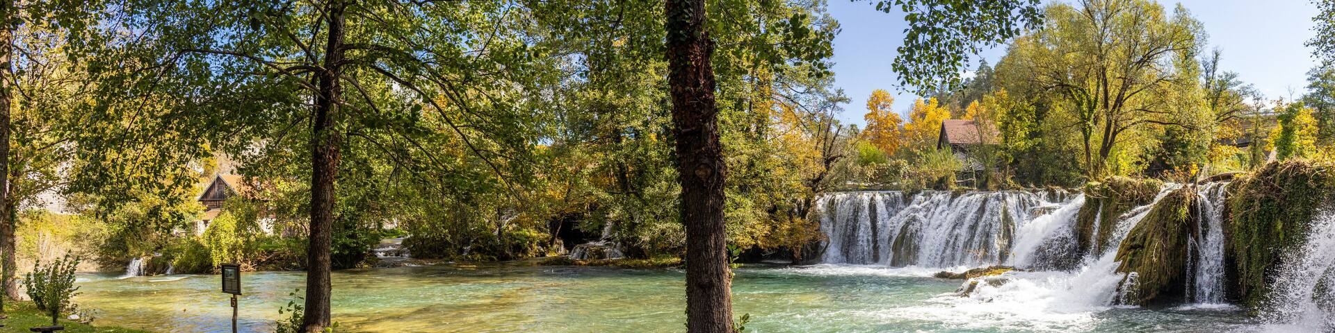 Panoramic photograph of the Rastoke Waterfalls, where the Slunjčica River meets the Korana River, creating a dreamlike landscape. Rastoke, Croatia