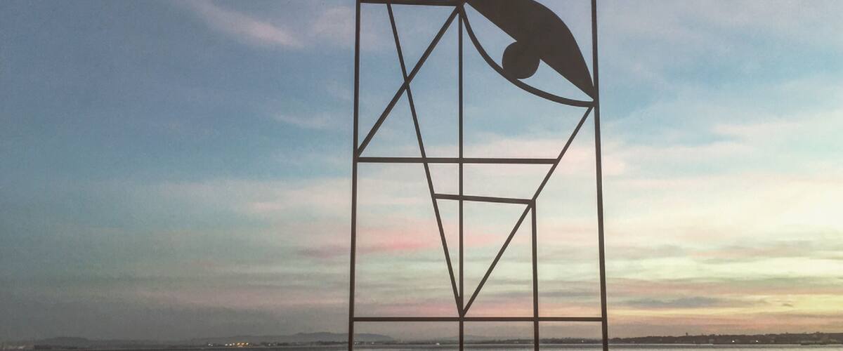 An artwork made by Almada Negreiros. In the other side of the river you can see Almada, a suburb of Lisbon with the same name as the artist