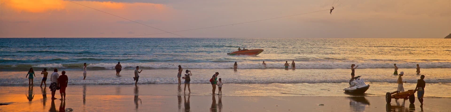 Patong som inkluderar en solnedgÄng, en sandstrand och vattensporter