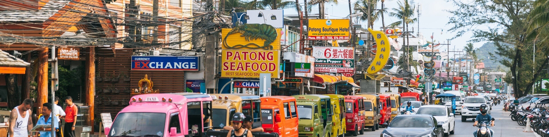 A busy street with colorful food trucks, a pink taxi, and motorcycles.