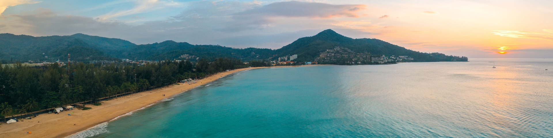 A coastal landscape with a beach, a mountain, and a sunset.