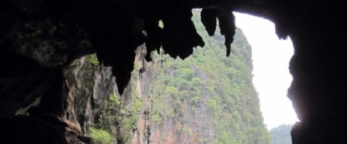 A cave opening with a river and a group of people kayaking.