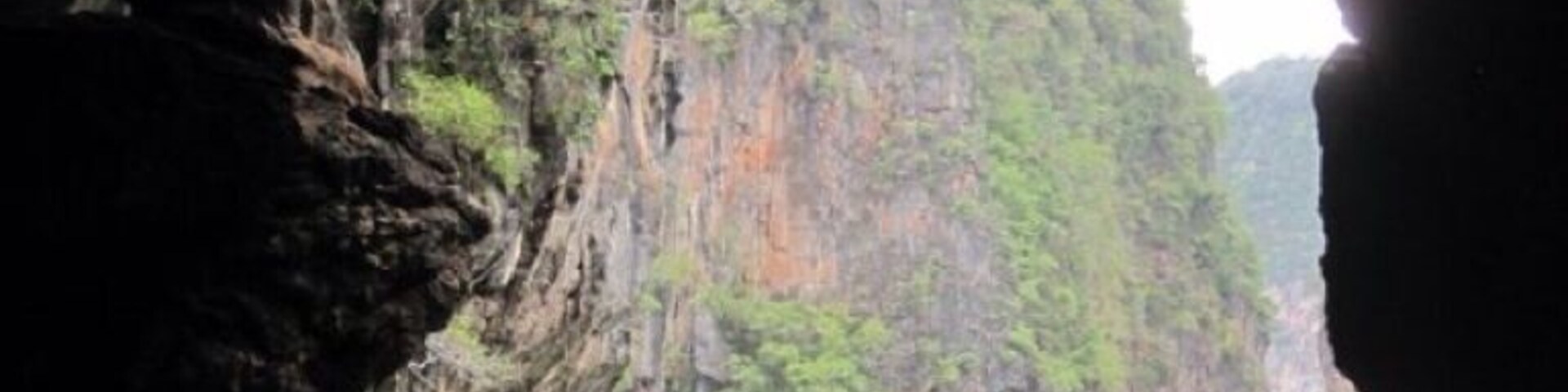 A abertura de uma caverna com um rio e um grupo de pessoas praticando caiaque.