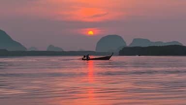 Rustig water bij zonsondergang, een boot en verre bergen.