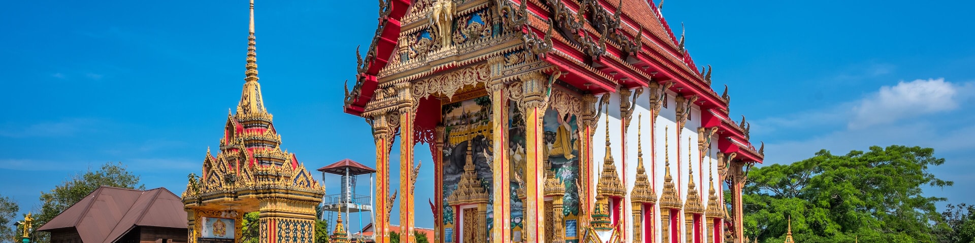A traditional Thai temple with ornate architecture and a smaller shrine.