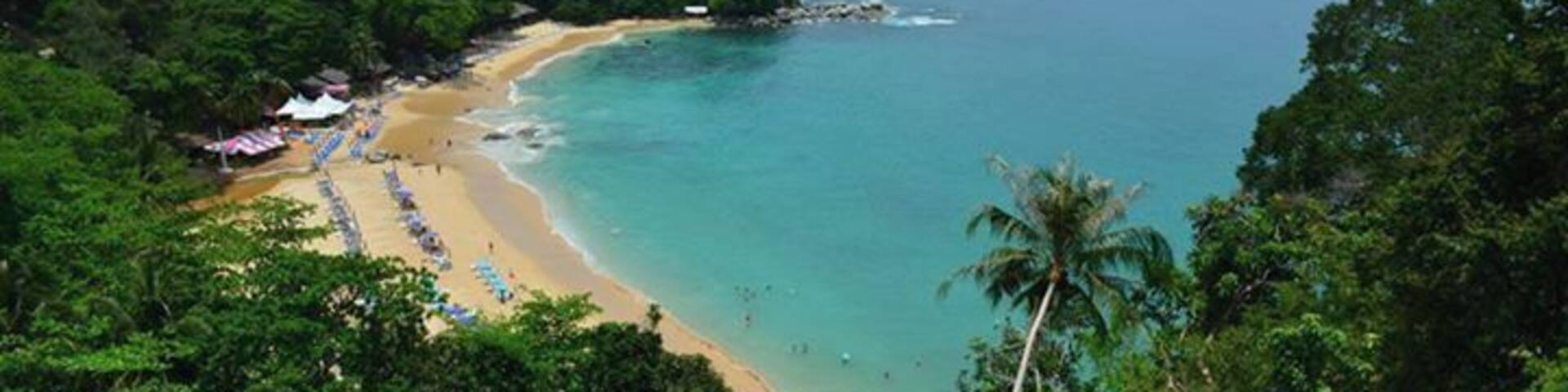 Une plage aux eaux turquoise et limpides, bordée d’un rivage sablonneux et d’une végétation luxuriante.