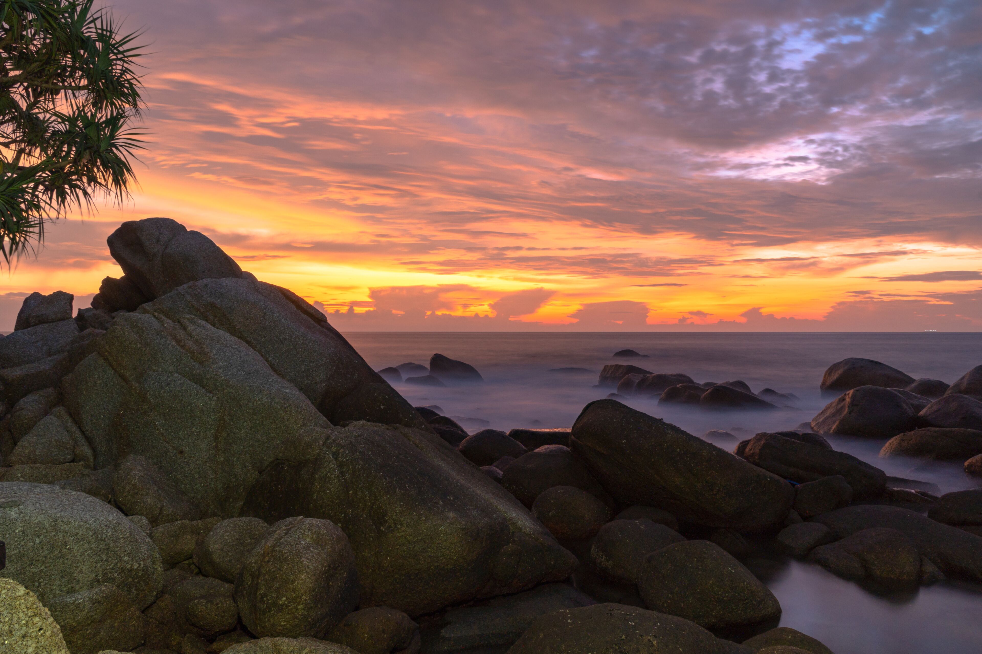 Orilla rocosa con grandes rocas y un cielo al atardecer.