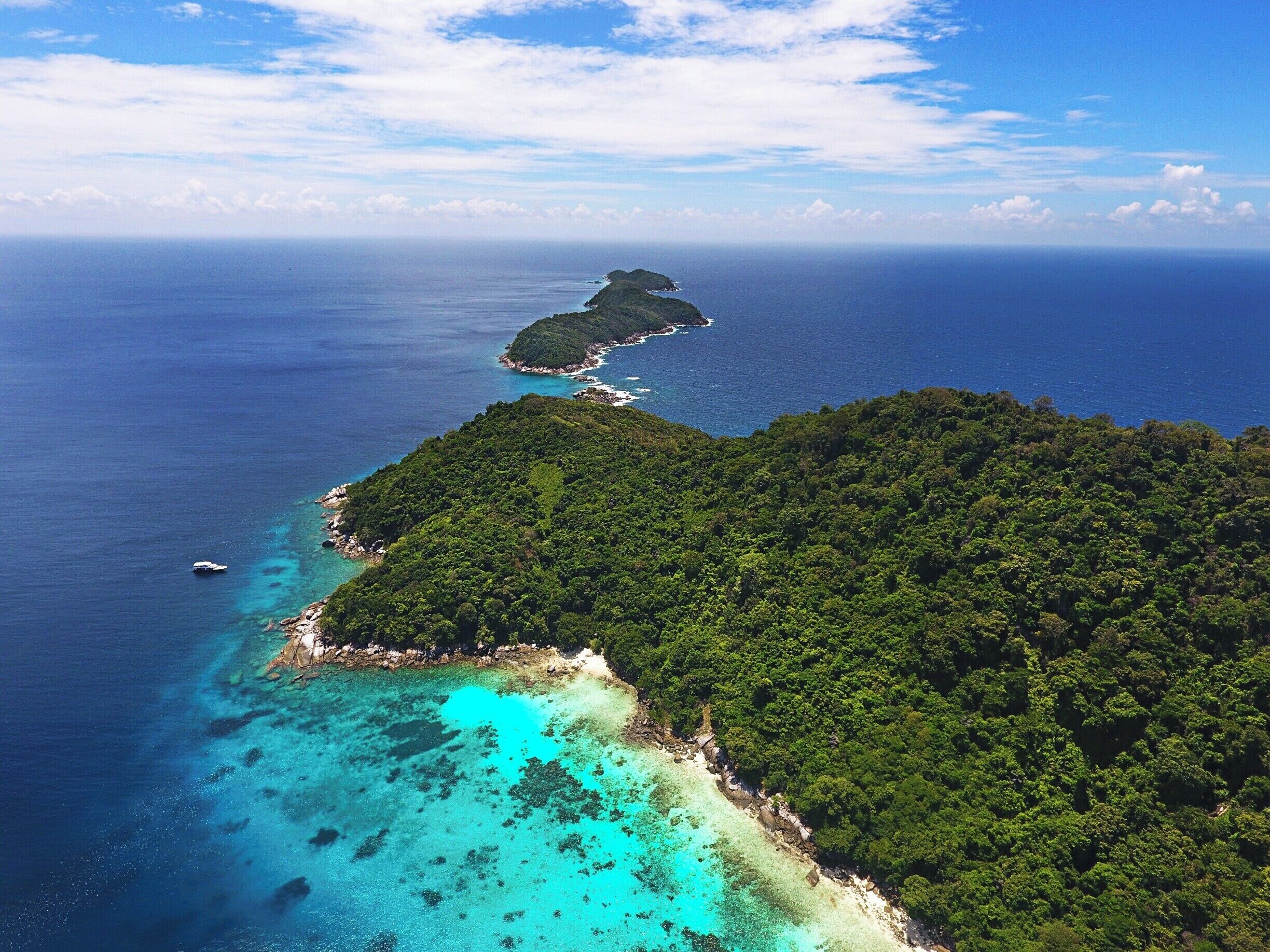 A tropical island with clear turquoise waters and dense green vegetation.