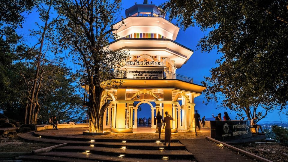 A multi-tiered pagoda with illuminated arches and a sign in a foreign script.