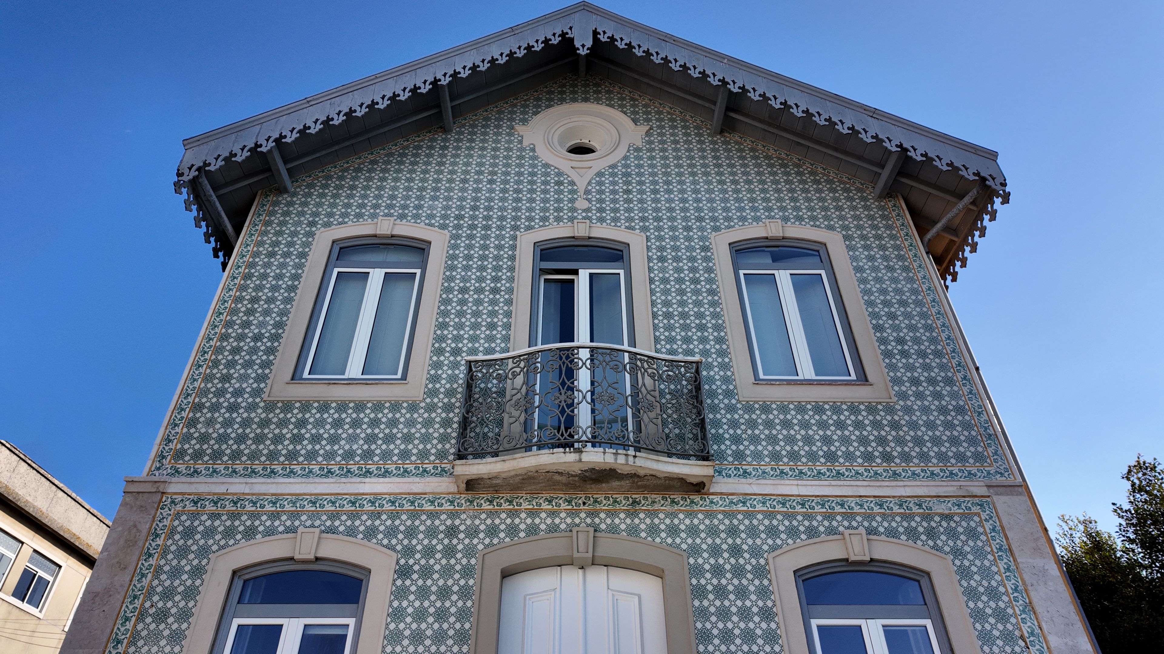 Historic Portuguese house with traditional green azulejo ceramic tile facade photographed from a low angle in Trafaria Almada Portugal