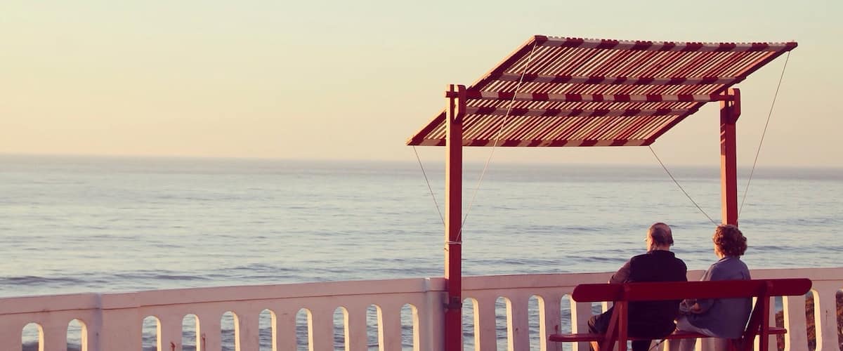 A wooden pier with a covered seating area overlooking the ocean.