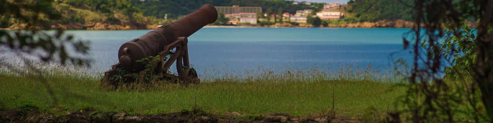 Old cannon in the fort is looking at sea with amazing clouds and island on background