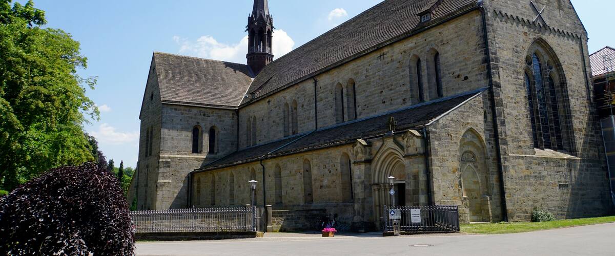 A large stone church with a tall steeple and a clock tower.