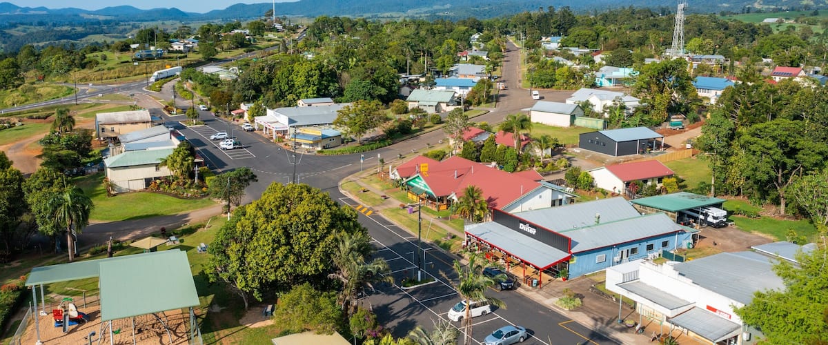 A small town with a main road, various buildings, and surrounding greenery.