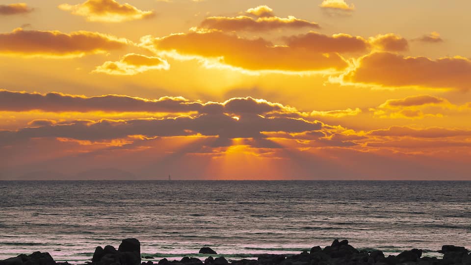 Winter and sunset view of seaside rock against sea horizon at Seonnyeobawi Beach of Eulwang-ri near Yongyu Island of Jung-gu, Incheon, South Korea