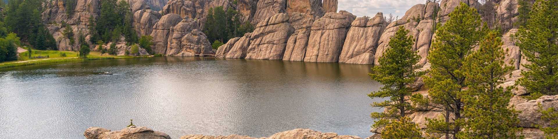Un lac entouré de grandes formations rocheuses et d’arbres.